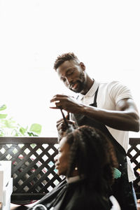 Male barber cutting hair of female customer in hair salon