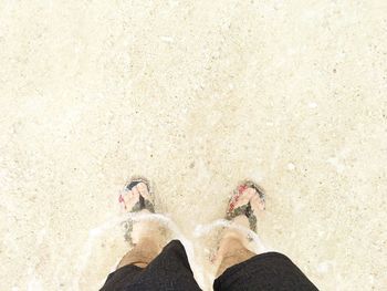 Low section of man standing on sand