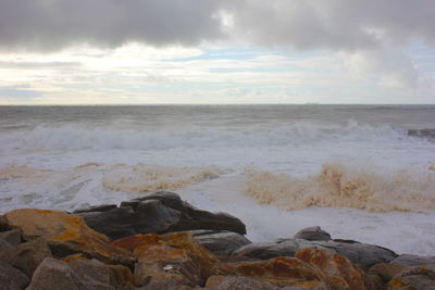 Scenic view of rocks on shore against sky