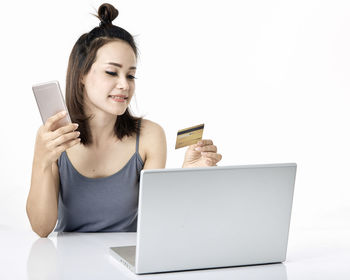 Young woman using smart phone against white background