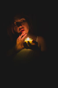 Close-up of woman holding lit tea light candle
