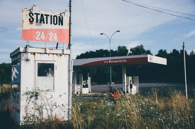 Text on old sign board at fuel pump against sky