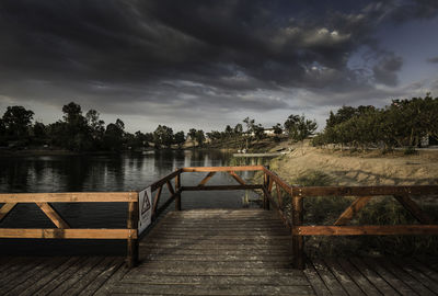 Empty pier over lake against sky