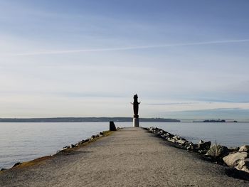 Man standing on groyne by sea against sky