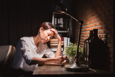 Young woman using phone while sitting on table