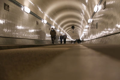 People walking in illuminated tunnel