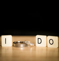 I do text amidst wedding rings on table against black background