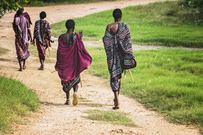 Rear view of people wearing traditional clothing while walking on land