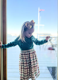 3-year-old girl in dress balancing at yacht club window