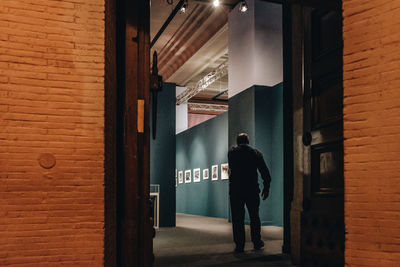 Rear view of man walking in illuminated building