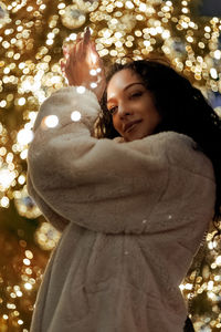 Portrait of smiling young woman standing while holding illuminated lights