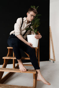 Full length of young man sitting on table