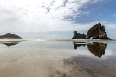 Rock formations on beach against sky