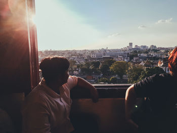 Rear view of man looking at cityscape against sky