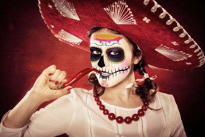 Portrait of woman with halloween make-up holding red chili pepper