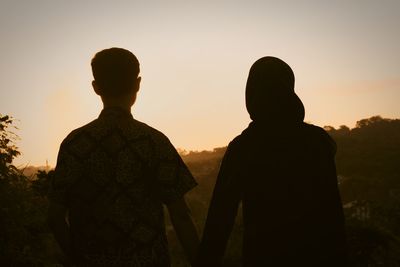 Rear view of silhouette man against sky during sunset