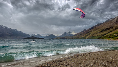 Scenic view of kiteboarding against sky