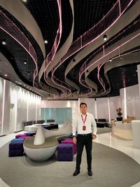 Full length portrait of man standing against illuminated ceiling