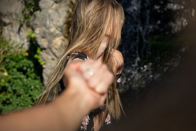 Close-up of young woman holding hand outdoors