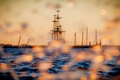 Sailboats sailing in sea against sky during sunset