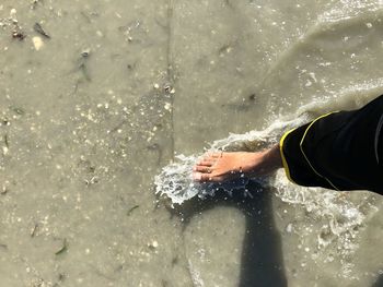 Midsection of person splashing water in sea