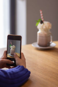 Female blogger taking photo or video of her chocolate milkshake to make a post in social media.
