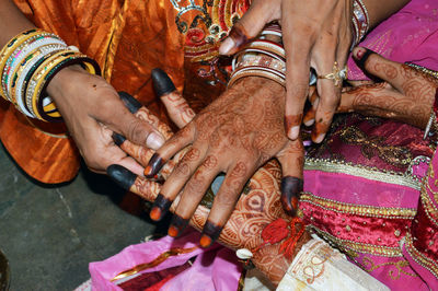 Bride and groom with henna painted hands completes hand matching ceremony in indian traditions.