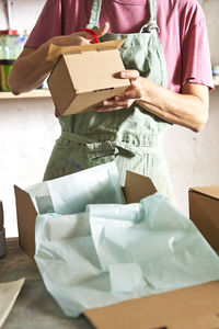 Female store owner cutting box while working in workshop