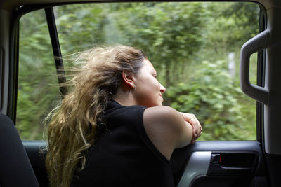 Young woman leaning out car window from car interior