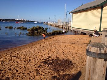 Boys playing on shore at beach against sky