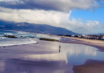 Scenic view of sea by snowcapped mountains against sky