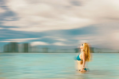 Woman standing in water against sky