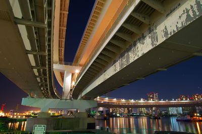 Low angle view of illuminated bridge over river at night