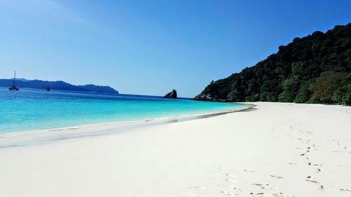 Scenic view of beach against clear blue sky