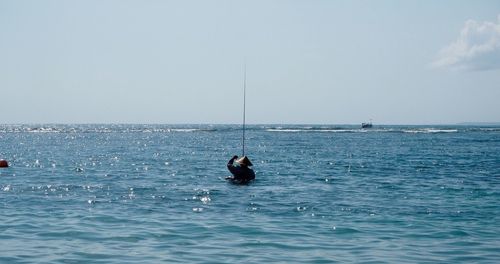 Man fishing in sea against clear sky