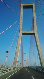 Low angle view of suspension bridge against blue sky