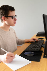 Young man using mobile phone while sitting on table