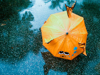High angle view of orange umbrella on wet footpath during rain