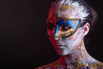 Portrait of man wearing mask against black background