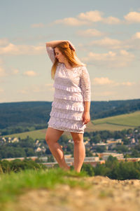 Woman standing on field against sky during sunset
