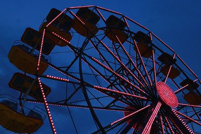 Low angle view of illuminated ferris wheel against blue sky