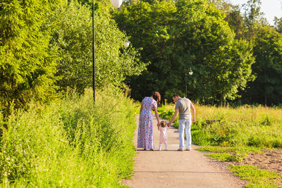 Rear view of people walking on footpath amidst plants
