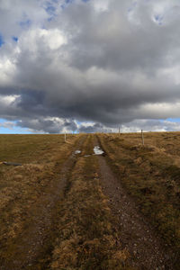 Road amidst field against sky
