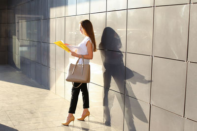 Woman with arms outstretched standing on floor in city