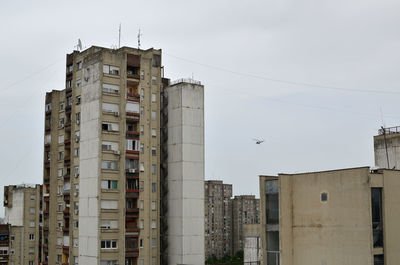 Police helicopter patrolling above a residential block in a city on grey cloudy sky