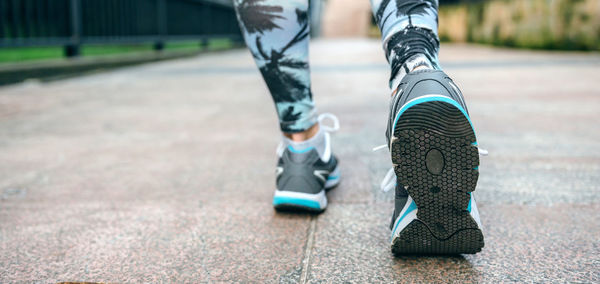 Woman legs ready to run wearing sneakers and tropical leggings