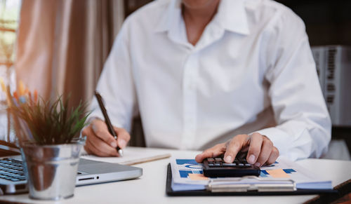 Midsection of businesswoman using mobile phone at office