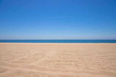 Scenic view of beach against clear blue sky