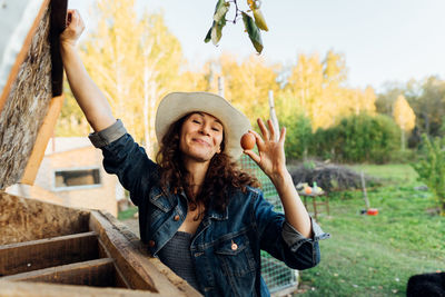 Portrait of smiling young woman standing against trees