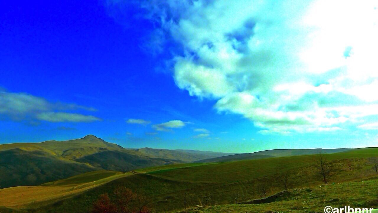 sky, landscape, tranquil scene, tranquility, mountain, blue, scenics, beauty in nature, nature, cloud - sky, cloud, grass, non-urban scene, mountain range, idyllic, field, remote, green color, countryside, sunlight